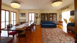 Un salón comedor espacioso con una gran mesa de madera, un sofá azul y dos candelabros.