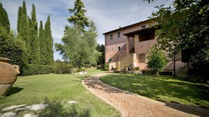 A paved pathway leading to a building with a brick facade and a stone wall.