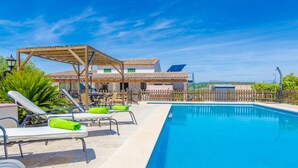 Un espace piscine avec des chaises longues et une pergola.