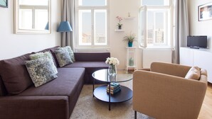 A modern living room with a brown sofa, a round glass coffee table, and a beige armchair.