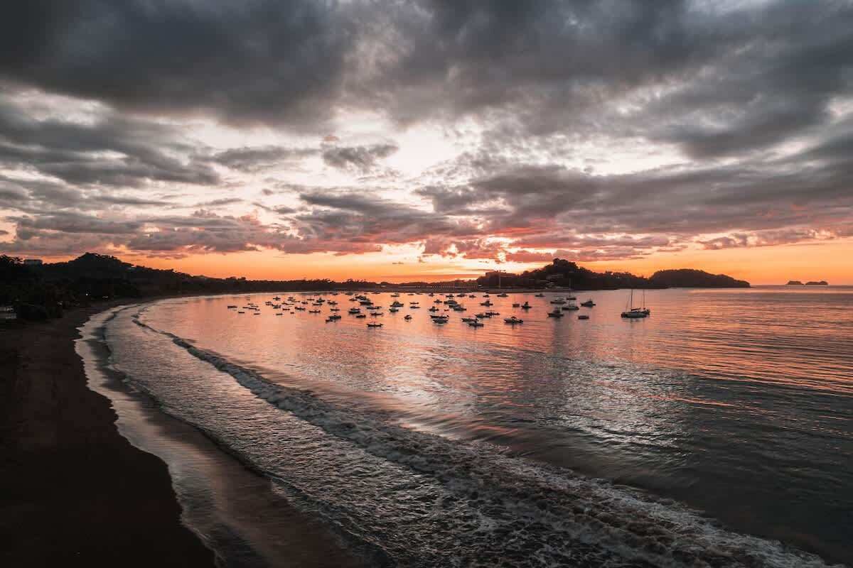 Une plage avec des bateaux et un coucher de soleil.