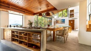 A spacious kitchen with wooden cabinetry, a large island, and a dining area with wooden chairs.