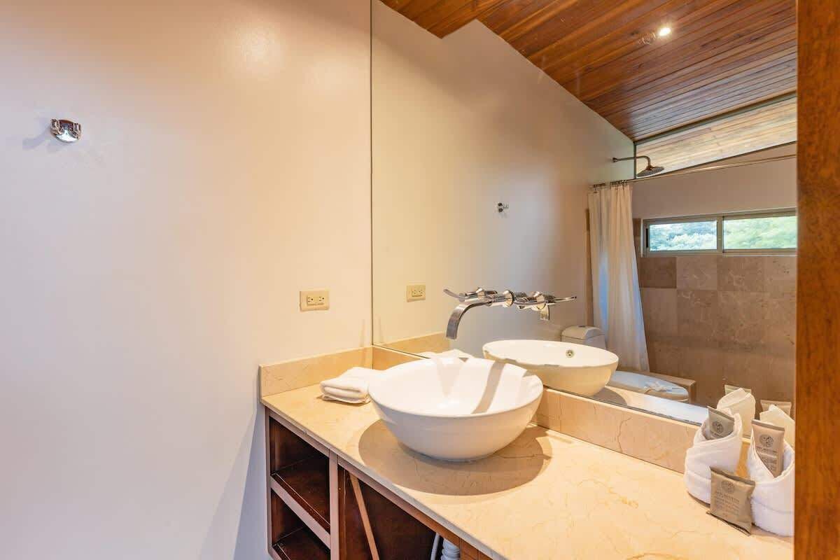 A modern bathroom with a large mirror, two sinks, and a shower area.