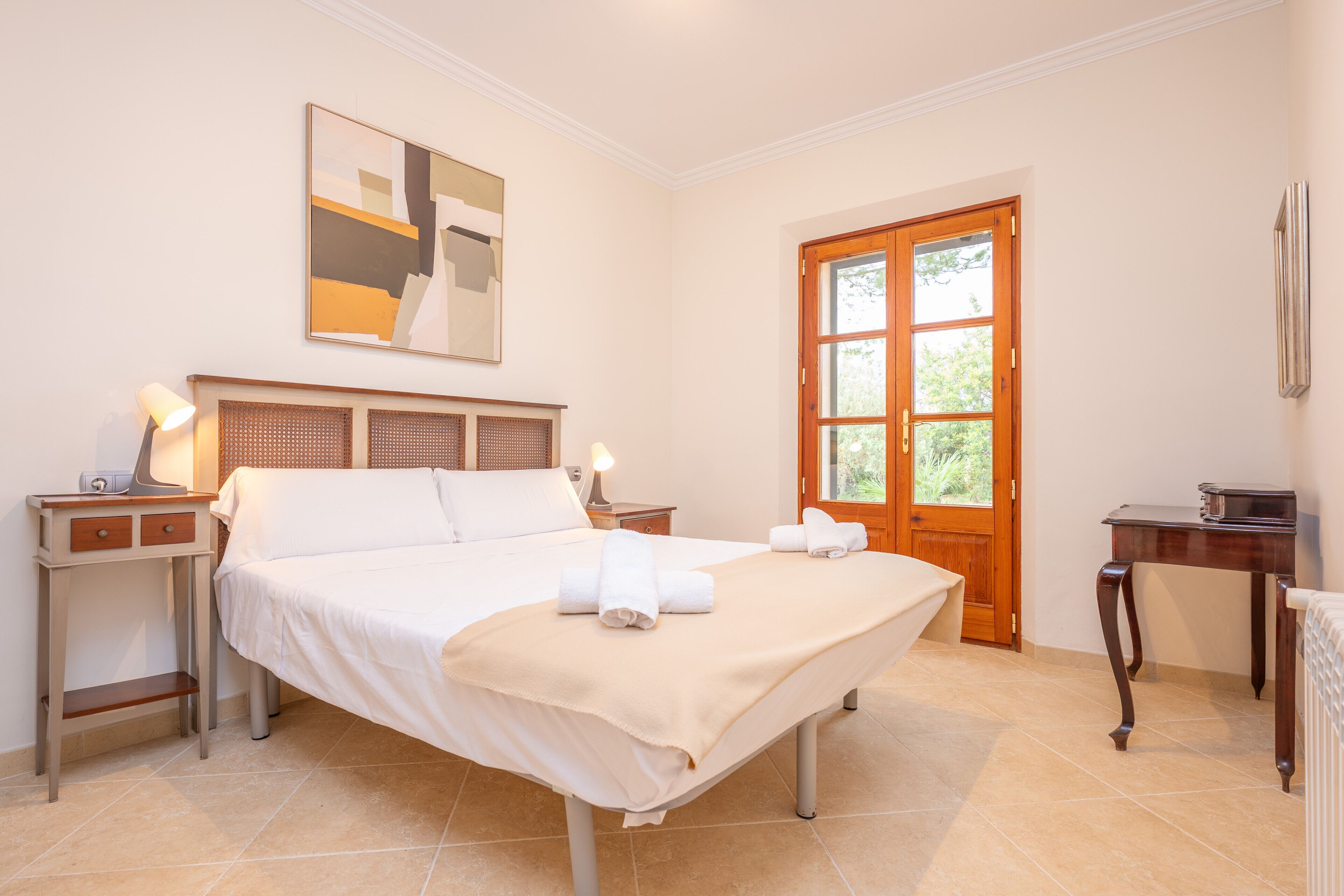 A neatly arranged bedroom with a bed, bedside tables, a wooden door, and a window.