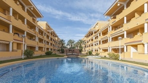 A hotel with a central swimming pool, multiple balconies, and a symmetrical facade. - CASCADES - Apartment with shared pool in Dénia. (Denia)