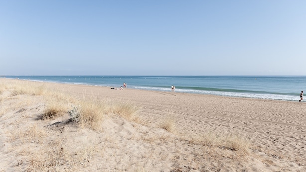 A wide sandy beach with gentle waves, a clear sky, and a few people in the distance. - CASCADES - Apartment with shared pool in Dénia. (Denia)