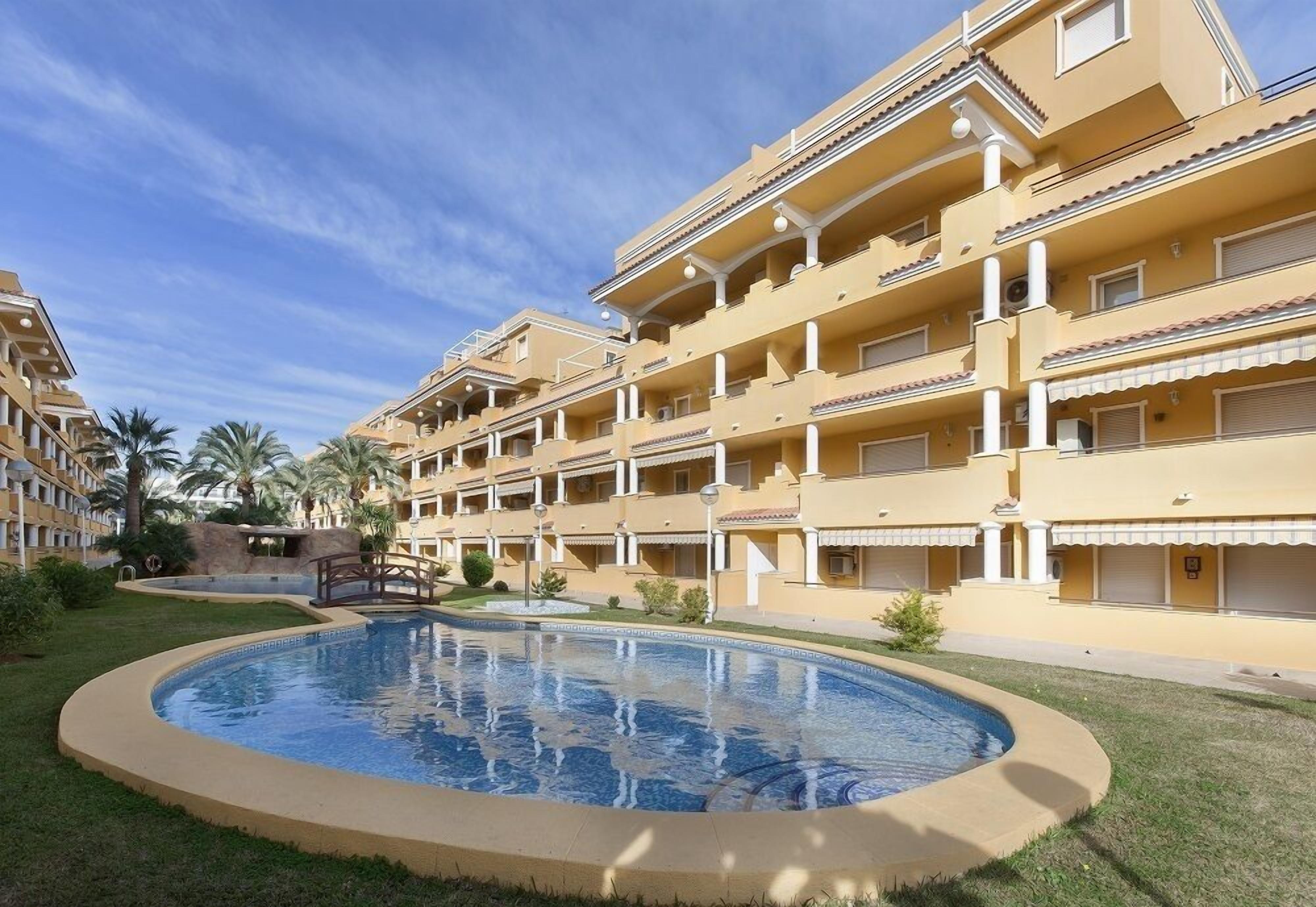 Ein Hotel mit mehreren Balkonen, einem Schwimmbad und Palmen.