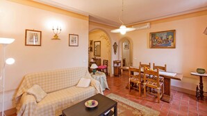 Una sala de estar con sofá, mesa de comedor, sillas y un ventilador de techo.