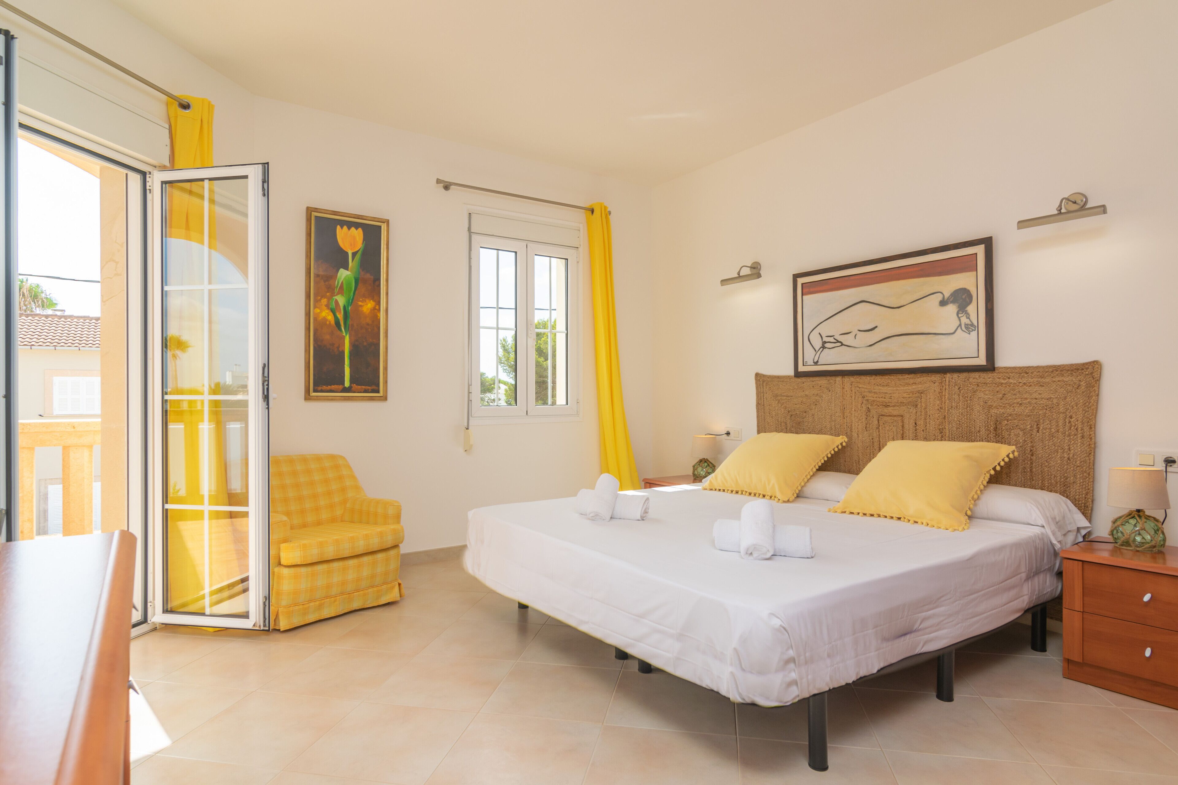 A bedroom with a bed, a chair, a window, and a painting on the wall.