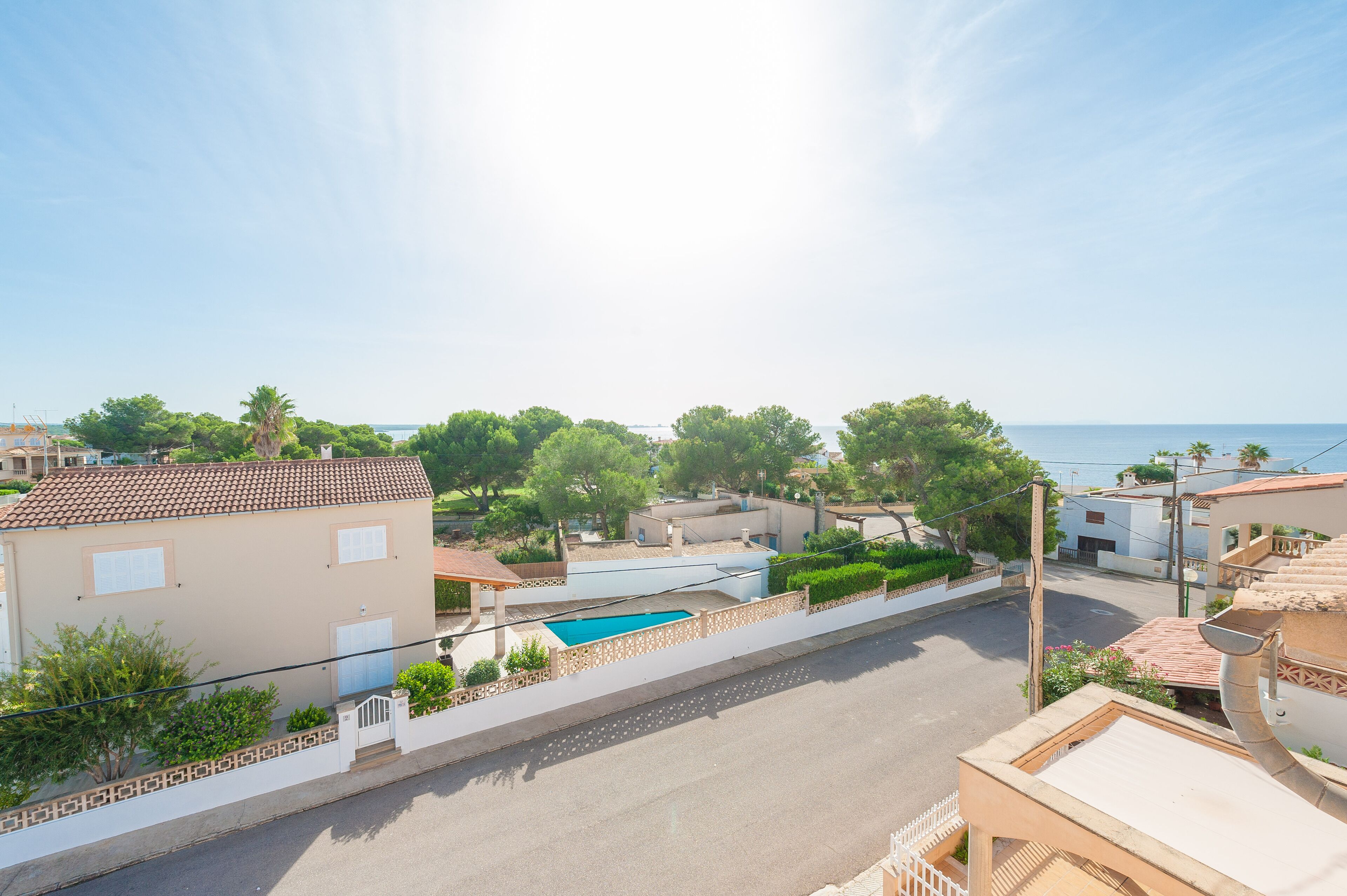 Zona residencial con piscina, casas y vista despejada al mar.