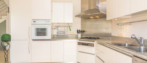 Une cuisine moderne avec des meubles blancs, un four encastré, une cuisinière et un lave-vaisselle Bosch.