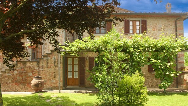 A stone building with a garden, a large pot, and a small tree. - Cosy apartment for 2 guests with WIFI, pool, TV and pets allowed, close to Cortona (Castiglion Fiorentino)