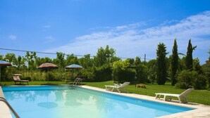 A swimming pool with lounge chairs and umbrellas, surrounded by greenery and trees. - Cosy apartment for 2 guests with WIFI, pool, TV and pets allowed, close to Cortona (Castiglion Fiorentino)