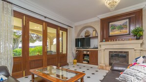 A spacious living room with a glass-top coffee table, leather sofa, and a fireplace.
