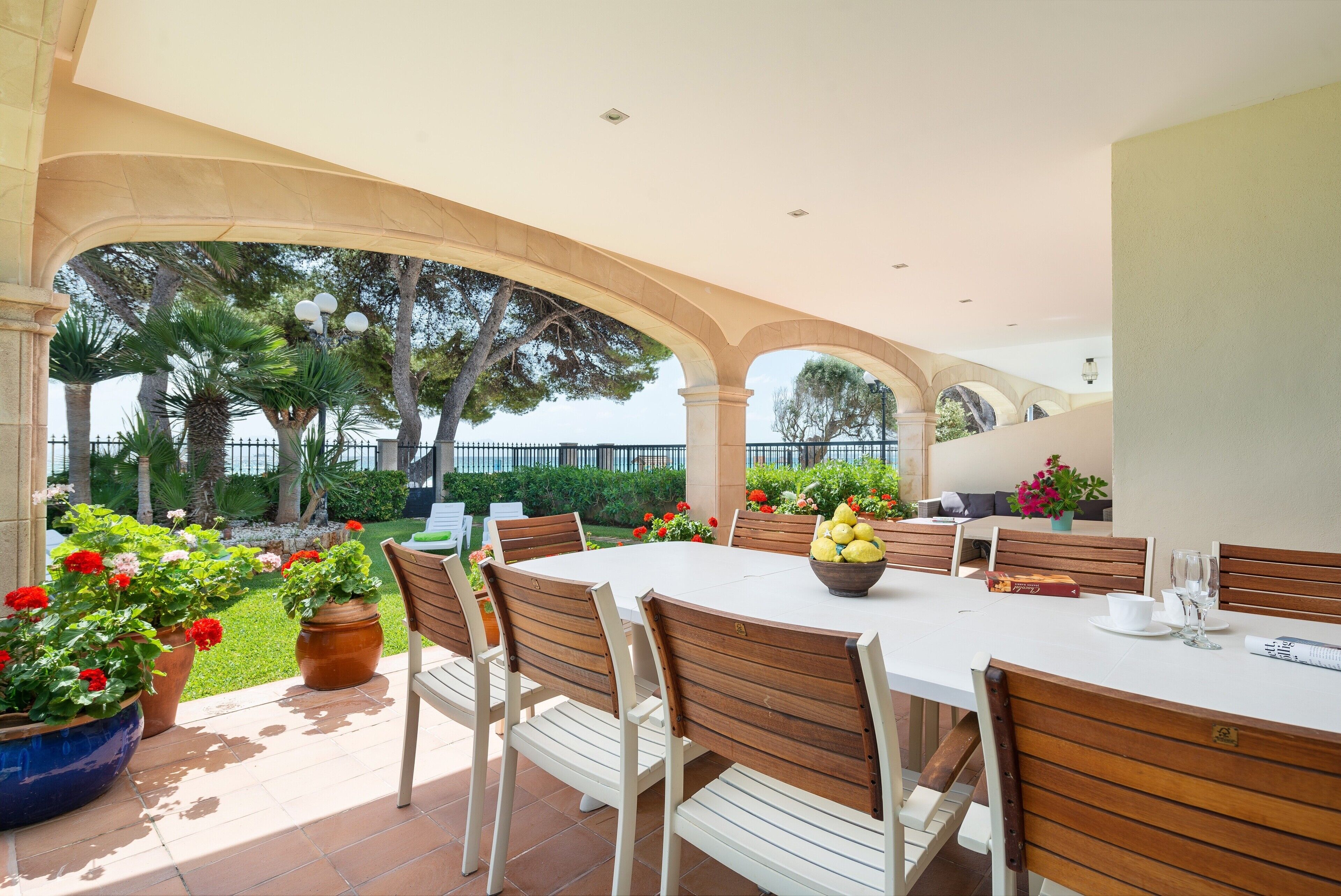 An outdoor patio with a round table, wooden chairs, and potted plants.