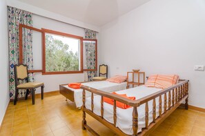 A room with two beds, a chair, and a window with curtains. - ES JAÇ - Villa with terrace in Cala s'Almonia with free Wi-Fi (Cala Llombards)