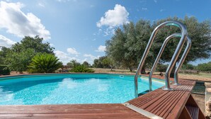 A wooden poolside deck with a metal ladder leading into a clear blue pool, surrounded by trees and greenery. - SON ROSSINYOL  - Beautiful country house with above ground pool in rural and quiet area. F (Llubí)