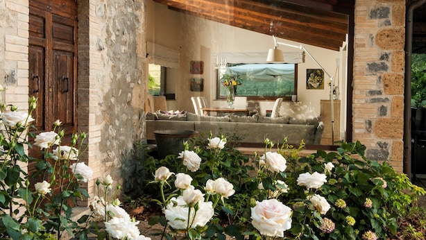 Un interior rústico con pared de piedra, puerta de madera y una zona de estar acogedora con sofá y mesa.
