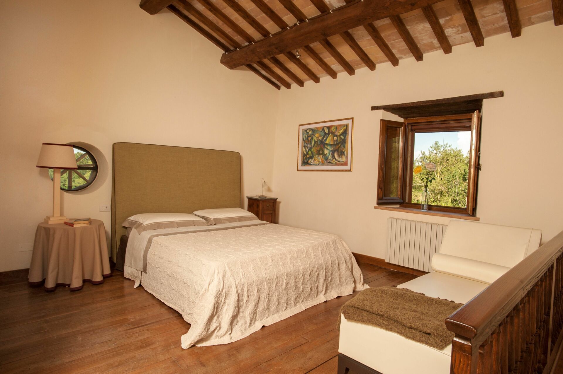 Une chambre à coucher avec un lit, une table de chevet, une lampe, une fenêtre et un radiateur.