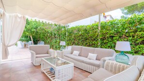An outdoor seating area with wicker furniture, a glass-top table, and a white canopy. - CAN FERRO - Villa with private pool in Cala Blava. Free WiFi (Llucmajor)