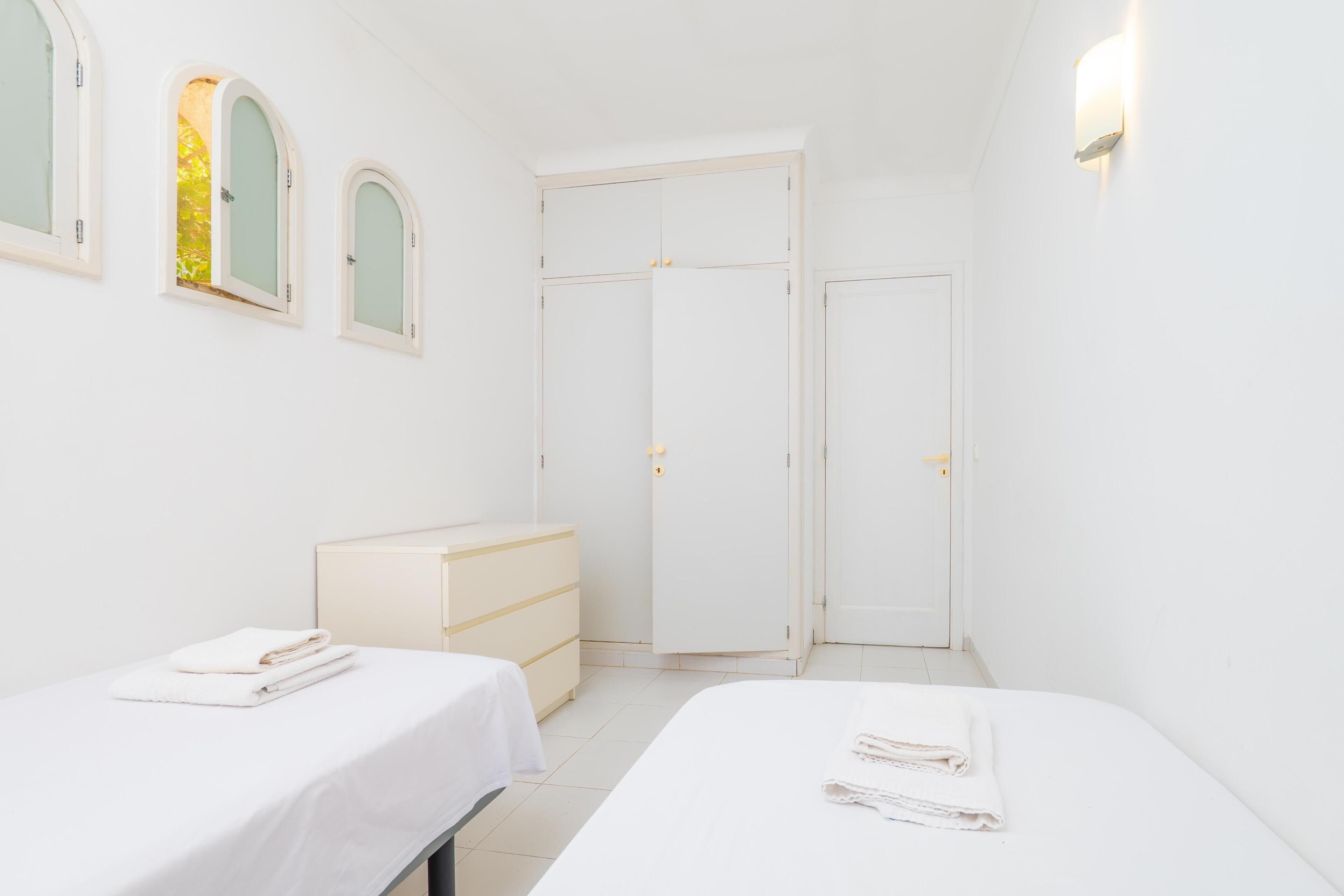 A room with two beds, a dresser, a wardrobe, and a mirror.