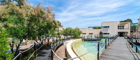 A wooden boardwalk leading to a pool area with a modern building in the background.