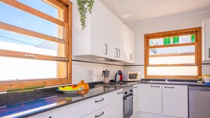 Une cuisine avec des meubles blancs, une cuisinière, un four à micro-ondes et un lave-vaisselle.