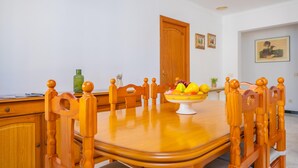 Un coin repas avec une table en bois, des chaises, un panier de fruits et une porte en bois.