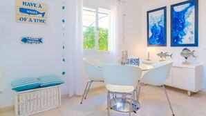 A dining area with a table, chairs, and decorative fish wall art. - BUGAMBILIA - Chalet with terrace in Sa Ràpita. Free WiFi (Sa Ràpita)