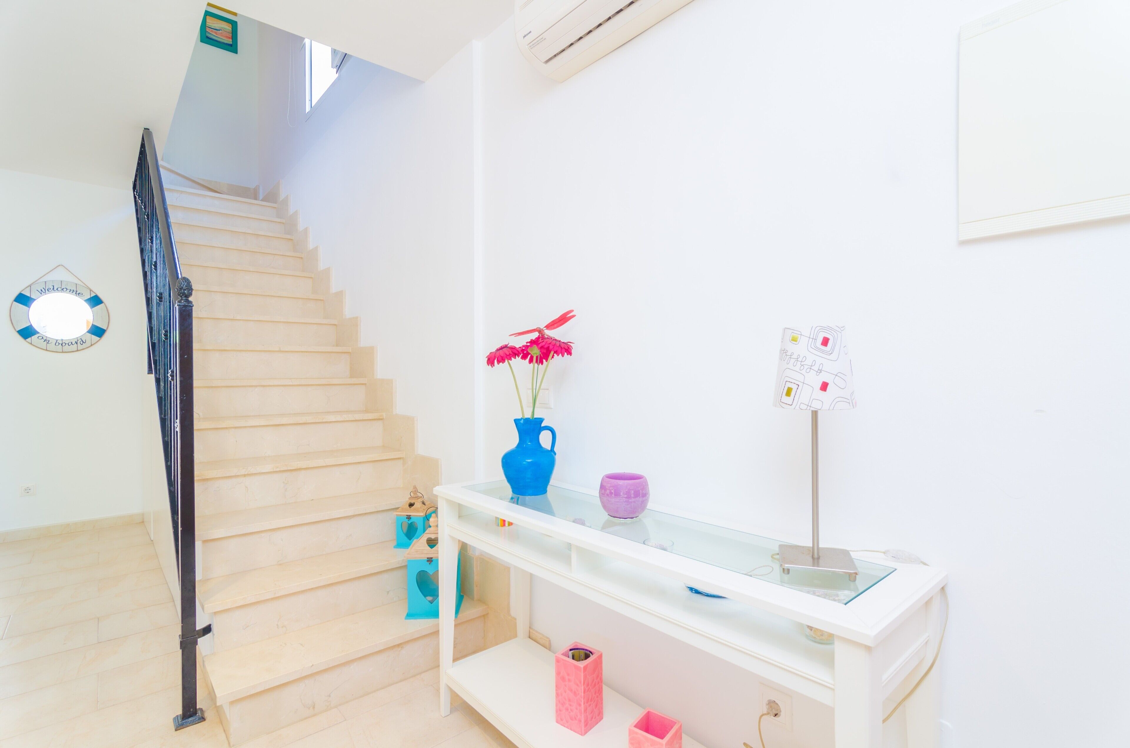 A staircase with a glass shelf holding a vase, a cup, and a small sign.