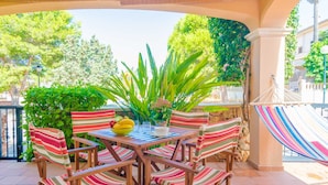 A patio area with a table set for four, surrounded by striped chairs, a yellow bowl, and a potted plant. - BUGAMBILIA - Chalet with terrace in Sa Ràpita. Free WiFi (Sa Ràpita)