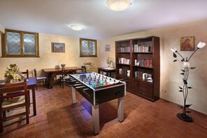 Relax in this inviting space with a foosball table at its center, surrounded by comfortable seating and a bookshelf.