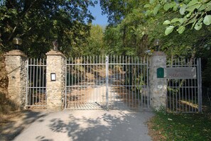 Enter Villa Le Ferme through a secure, gated entrance surrounded by lush greenery.