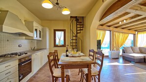 Una cocina amplia con comedor, sillas de madera y una escalera.