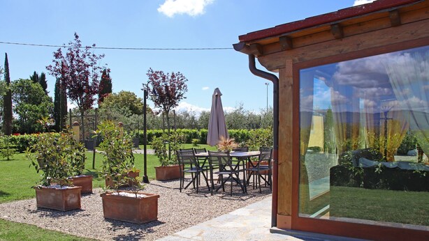 Un patio con mobiliario exterior, macetas con plantas y vistas a un jardín.