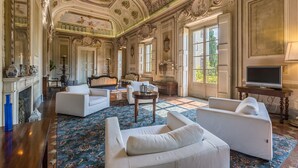 Une chambre luxueuse, ornée de fresques au plafond, dotée de grandes fenêtres et meublée dans un style classique.
