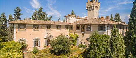 A historic building with a tower, terraced gardens, and a courtyard.