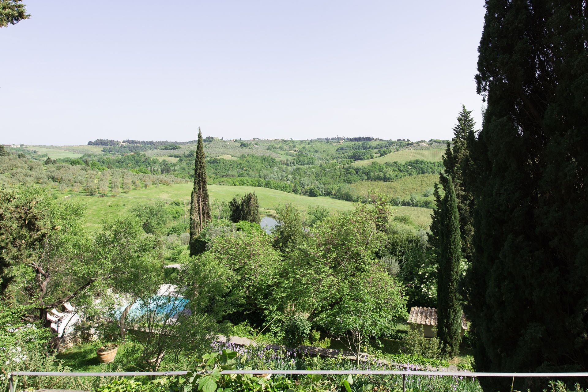 A lush green landscape with rolling hills, a tall tree, and a small building with a tiled roof.