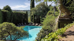 Une piscine entourée d’une végétation luxuriante et de statues en pierre.