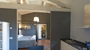 Une chambre d’hôtel de taille réduite, comprenant un lit, une table de chevet et une petite kitchenette.