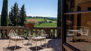 Ein Balkon mit Blick auf sanfte Hügel, einem Blumentopf und Gartenmöbeln.