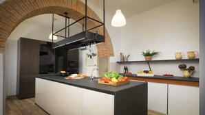 A modern kitchen with an island, a brick arch, pendant lights, and a wooden countertop. - Villa Giare - Villa with private pool (Fratticciola)
