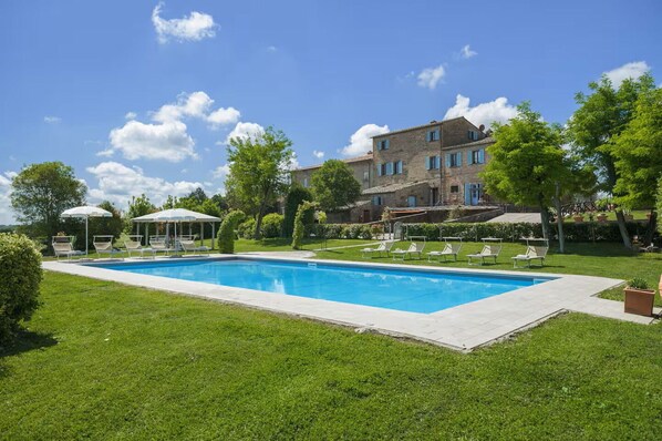 A swimming pool with lounge chairs, a gazebo, and a large building with multiple windows. - Villa Giare - Villa with private pool (Fratticciola)
