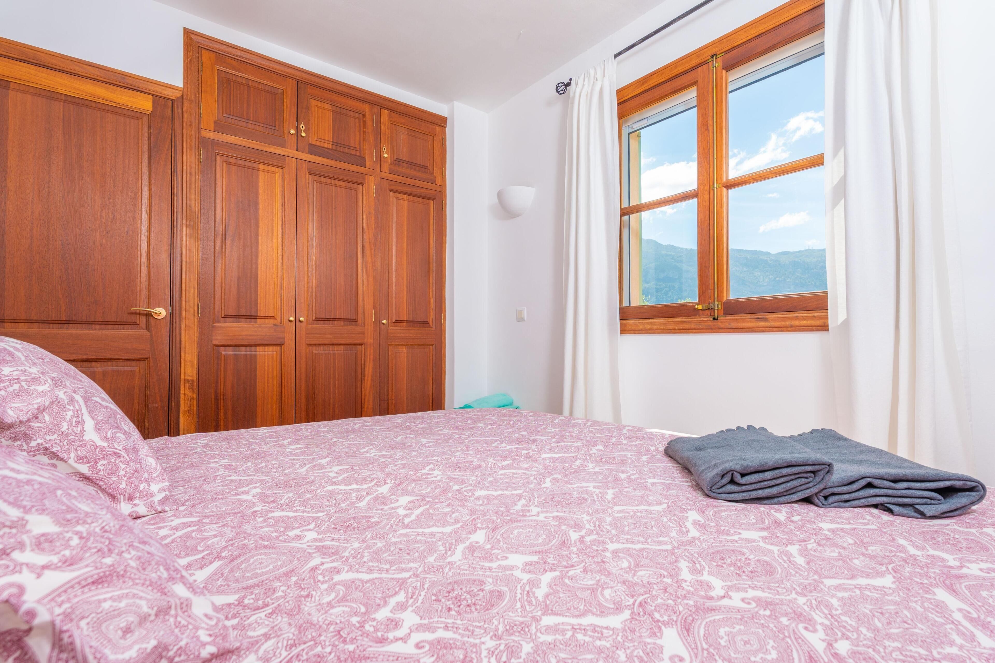 Ein Schlafzimmer mit Bett, Holzschrank und einem fenster mit Vorhängen.