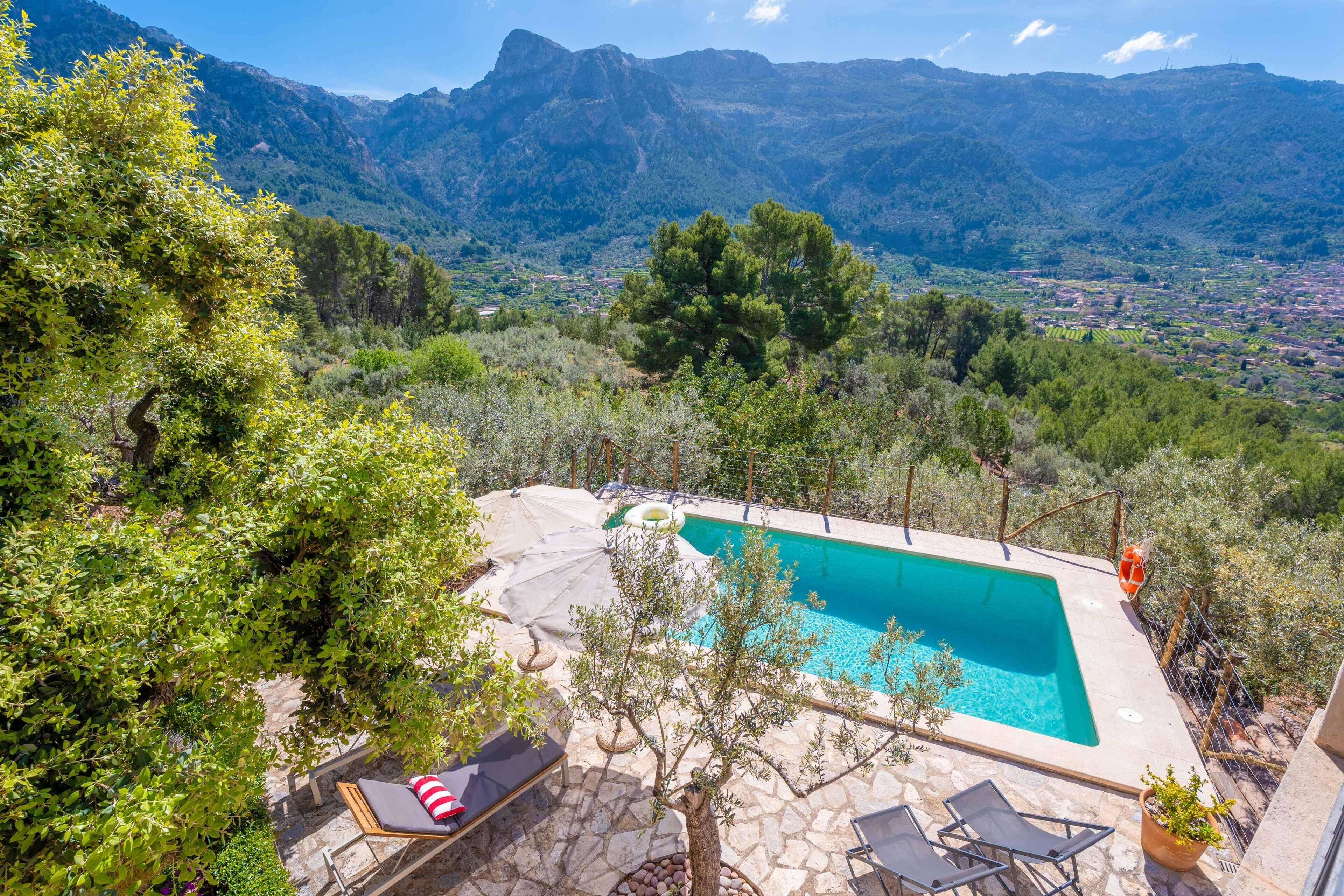Piscina con vista a la montaña, mobiliario exterior y terraza de piedra.