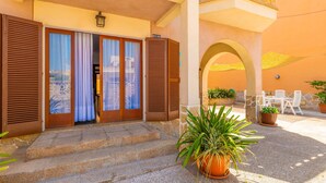 A hotel entrance with a set of stone steps, a wooden door with shutters, and a balcony with a railing. - CAN PEDRO ROS - Lovely chalet with a terrace in s’Illot and free Wi-Fi (S'ILLOT)