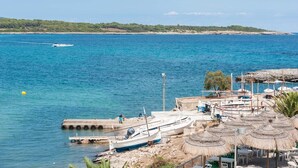 A coastal marina with boats docked, a sandy beach, and thatched umbrellas. - CAN PEDRO ROS - Lovely chalet with a terrace in s’Illot and free Wi-Fi (S'ILLOT)