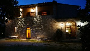 Un edificio in pietra con un ampio ingresso ad arco e un balcone al secondo piano.