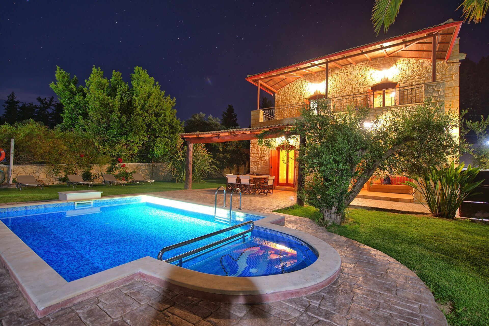 A stone house with a swimming pool, outdoor seating, and a covered patio area.