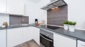 Eine moderne Küche mit weißen Schränken, einer dunklen Arbeitsplatte und einem Einbauofen.